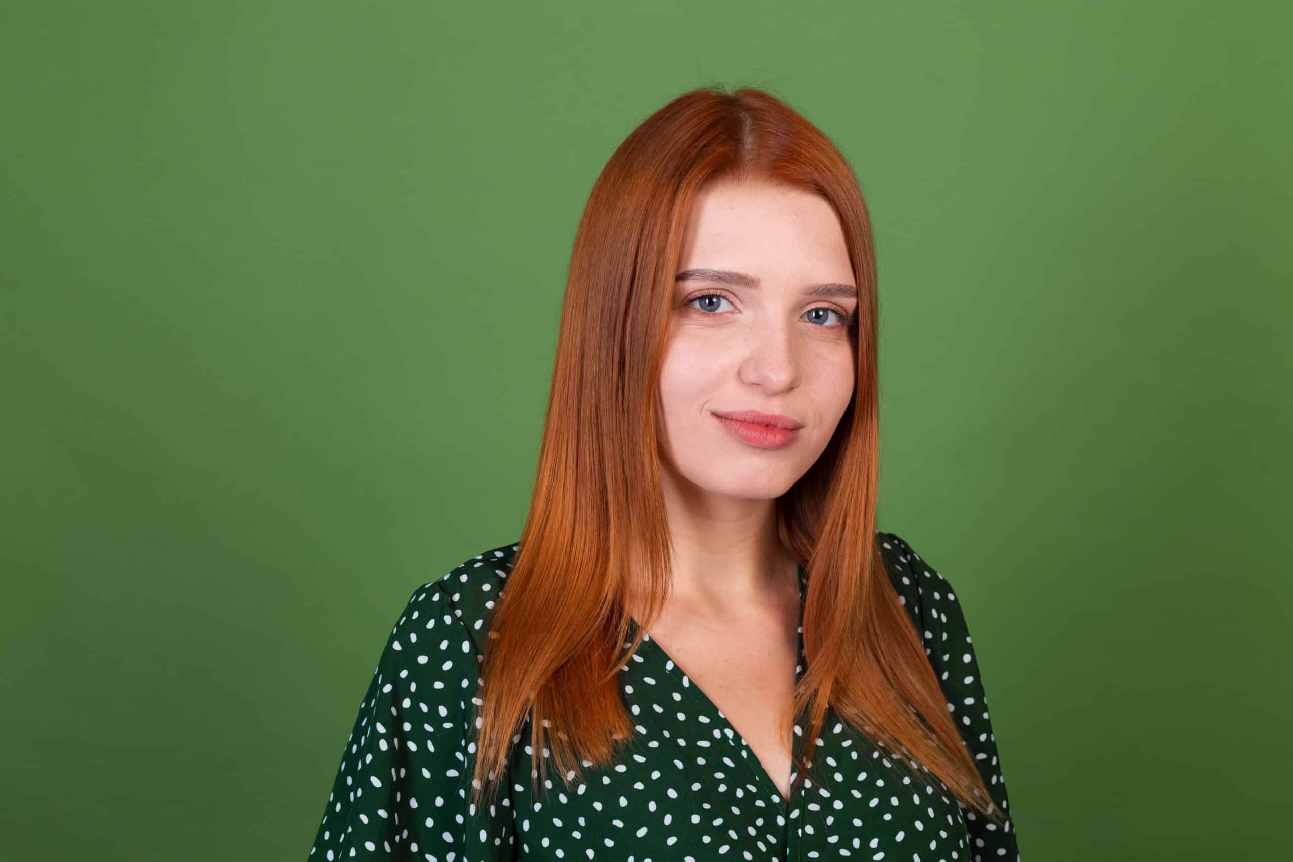 Young red hair woman on green background with confident smile look to camera
